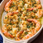 baked shrimp oreganata with garlic butter sauce and crispy breadcrumbs in a baking dish